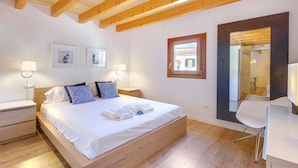 Une chambre à coucher avec un lit en bois, deux tables de chevet, un bureau et une chaise.