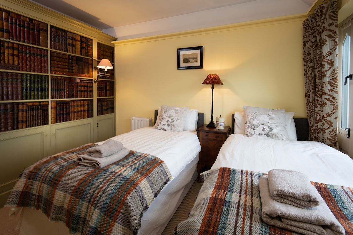 Une chambre d’hôtel avec deux lits, une bibliothèque, une lampe et un tableau encadré au mur.