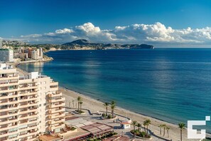 A coastal hotel with multiple floors, a beach promenade, and a view of the sea and distant hills. - Apolo XVI 73 - Grupo Turis - Calpe, Costa Blanca (Calpe)