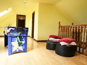 Ein Zimmer mit einem Kicker, zwei schwarzen Hocker mit Handtüchern, einer Holzreling und einer Tür im Hintergrund.