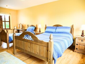 A bedroom with two wooden beds, a nightstand, and a window with curtains.