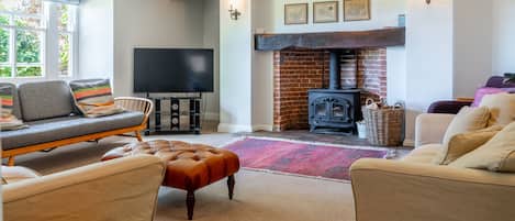 A cozy living room with a fireplace, comfortable seating, and a flat-screen TV.