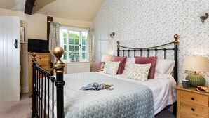 A bedroom with a bed, bedside table, lamp, and a window with curtains.