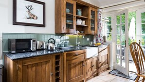 A kitchen with wooden cabinets, a microwave, a kettle, and a sink.