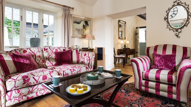 A living room with a sofa, armchair, coffee table, and a painting on the wall.