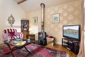 A cozy living room with a fireplace, a sofa, a television, and a decorative mirror.
