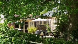 A patio area with a table and chairs, a wooden fence, and a building with stone walls and windows.