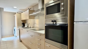 Una cocina moderna con electrodomésticos de acero inoxidable, armarios de madera clara y un horno empotrado.