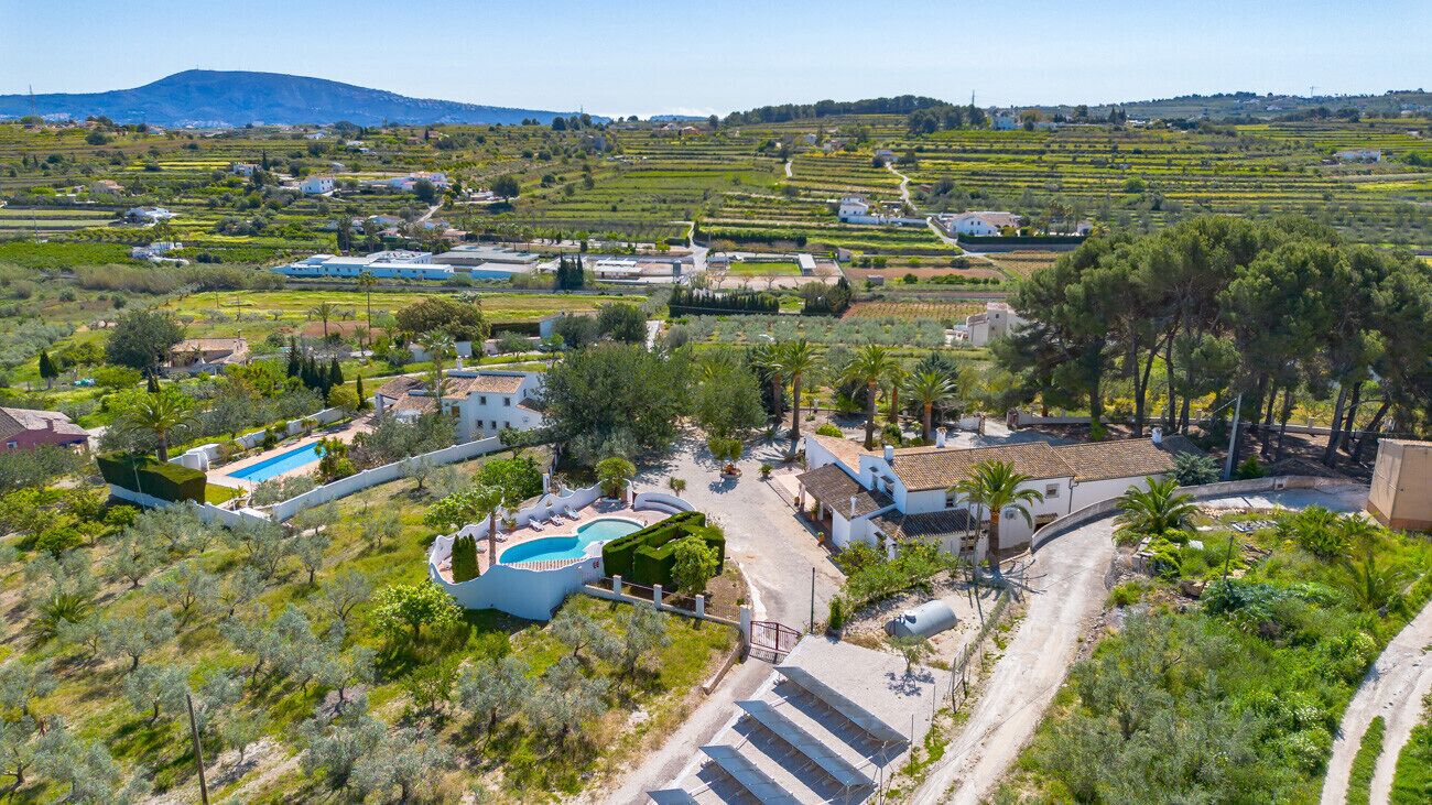 Vue aérienne d’une propriété dotée d’une piscine, de champs en terrasses et d’un paysage montagneux en arrière-plan.