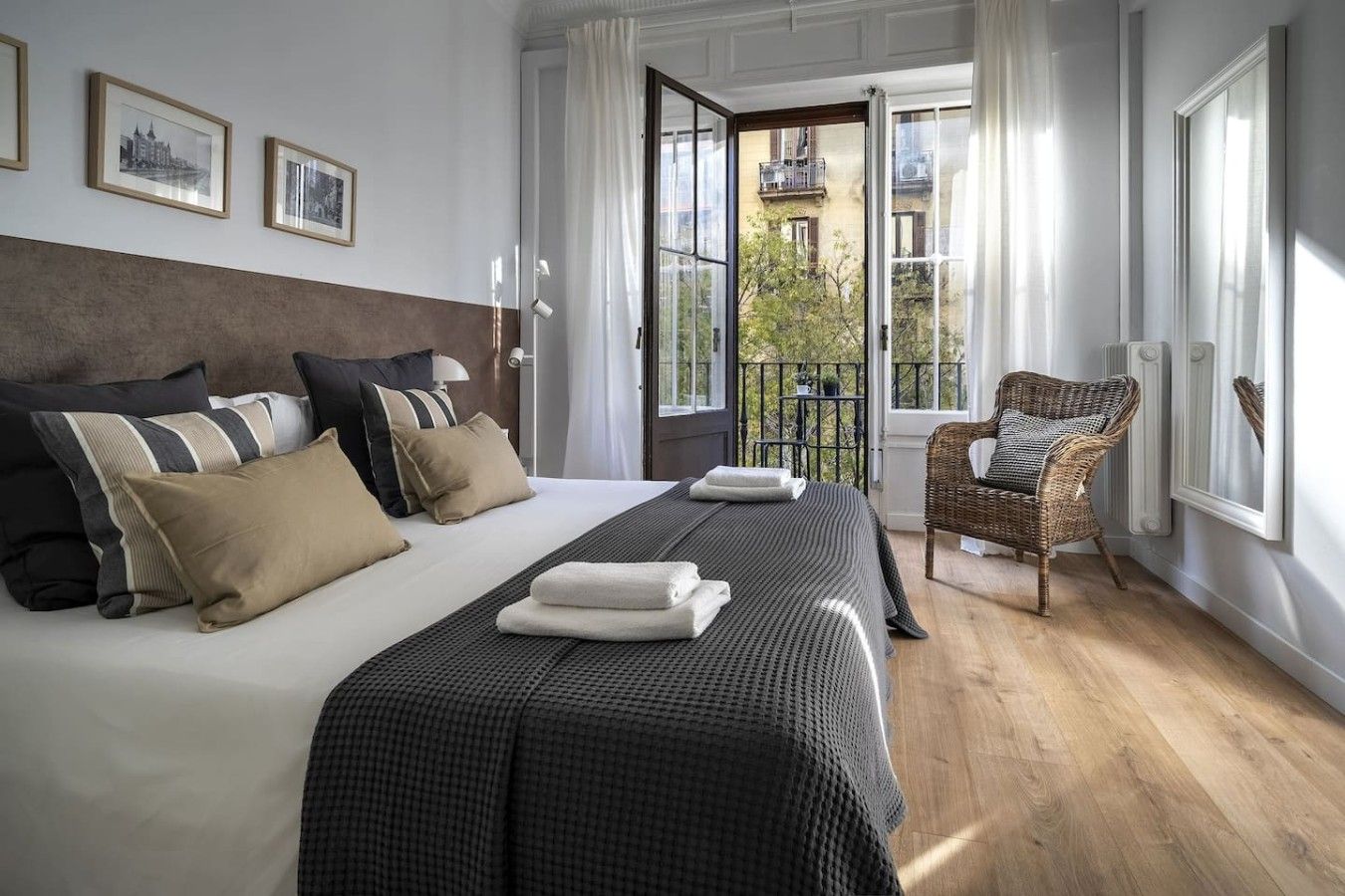 A hotel room with a large bed, a wicker chair, and a view of the outside.