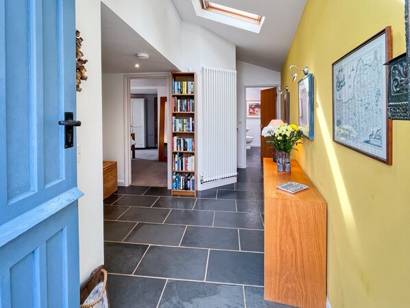 Un couloir avec une porte bleue, un comptoir d’accueil en bois, une bibliothèque et un radiateur.