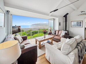 Un salon moderne doté d’une grande fenêtre donnant sur un paysage magnifique, d’une cheminée et d’un coin salon confortable.