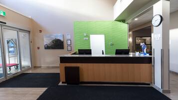 A reception desk with a green textured wall, a clock, and a framed picture on the wall.