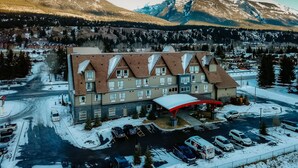 Un hôtel à plusieurs étages doté d’une cour intérieure, entouré de routes enneigées et ayant une chaîne de montagnes en toile de fond.