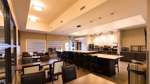 Un restaurant moderne doté d’un bar central, de tables et de chaises.