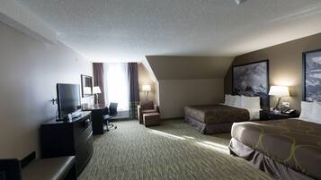 Quarto de hotel com televisão de tela plana, escrivaninha, duas camas, sofá e uma janela grande com cortinas.