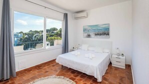 A bedroom with a large window, a bed, a nightstand, and a painting on the wall. - Villa Mascaro - Six Bedroom Villa, Sleeps 12 (Serpentona)
