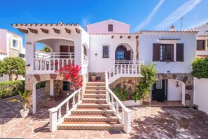 A white building with a stone facade, a staircase leading to a balcony, and a door with a star decoration.