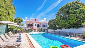 A swimming pool with lounge chairs, a wooden fence, and a building in the background. - Villa Mascaro - Six Bedroom Villa, Sleeps 12 (Serpentona)