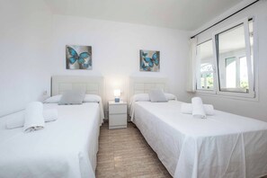 A hotel room with two beds, white bedding, a nightstand with a lamp, and butterfly artwork on the walls.