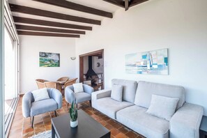 Una sala de estar con un sofá, dos sillones, una mesa de centro y un cuadro en la pared.