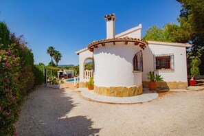 Una casa blanca con un patio circular, piscina y un pequeño jardín.