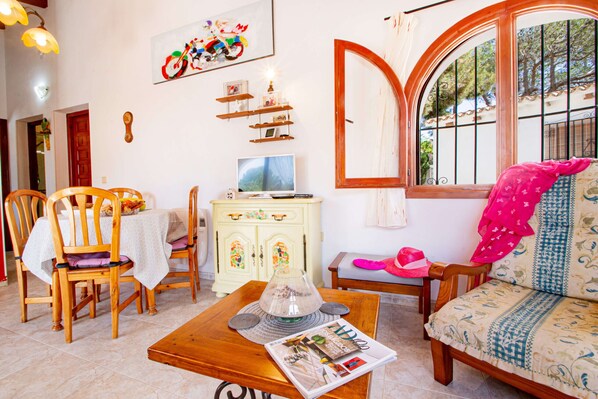 Una sala de estar acogedora con una mesa de madera, sillas, un sofá y un televisor.