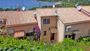 A coastal residential area with terracotta-tiled buildings, satellite dishes, and lush greenery. - Terraced house with 3 bedrooms and garden, only 100m. from the beach (Grosseto-Prugna)