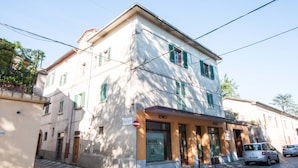 A two-story building with a ground-floor entrance, a sign indicating a restaurant, and a parked car in front. - Appartamento Bell - 2, 4 persone (Sansepolcro)