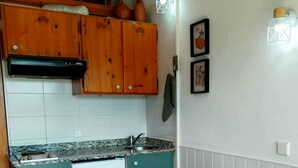 Una cucina compatta con mobili in legno, un frigorifero bianco e un tavolo da pranzo in legno con sedie bianche.