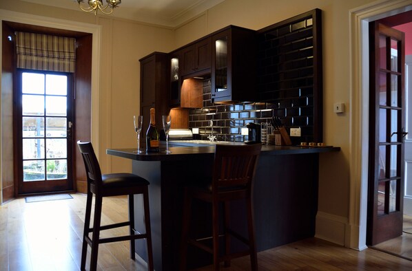 Una cocina con armarios de madera oscura, una encimera negra y dos taburetes de bar.