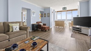 A living room with a sofa, armchairs, a coffee table, and a TV. - 3 Bed in Woolacombe (oc-1devo) (Woolacombe)