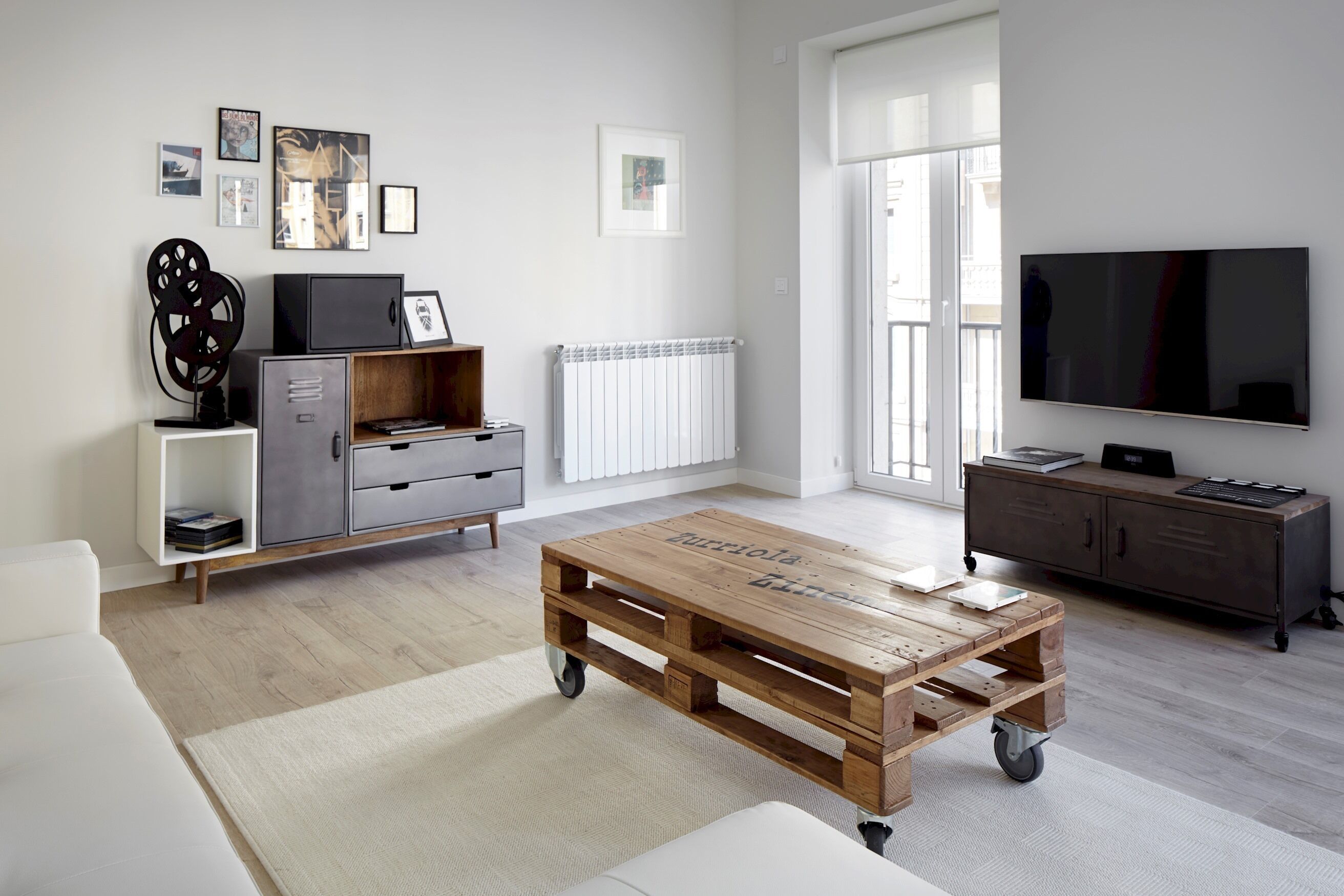 Een moderne woonkamer met een houten salontafel, een grijze kast, een witte bank en een flatscreen televisie.