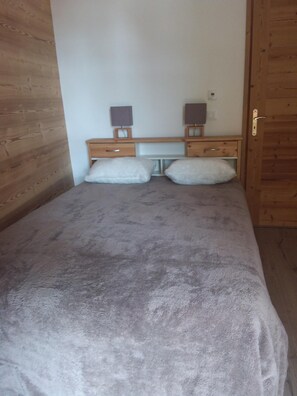 A bedroom with a bed, two bedside tables, and a wooden door.