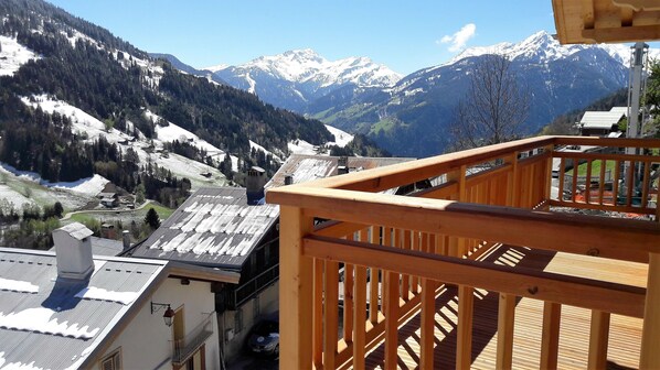 A wooden balcony overlooking a snowy mountain landscape with buildings in the foreground. - Rent New apartment 64m2 in Chalet in the heart of the village of Hauteluce (Hauteluce)
