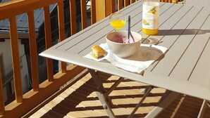 Um deck de madeira com uma mesa posta para café da manhã, com vista para montanhas cobertas de neve.