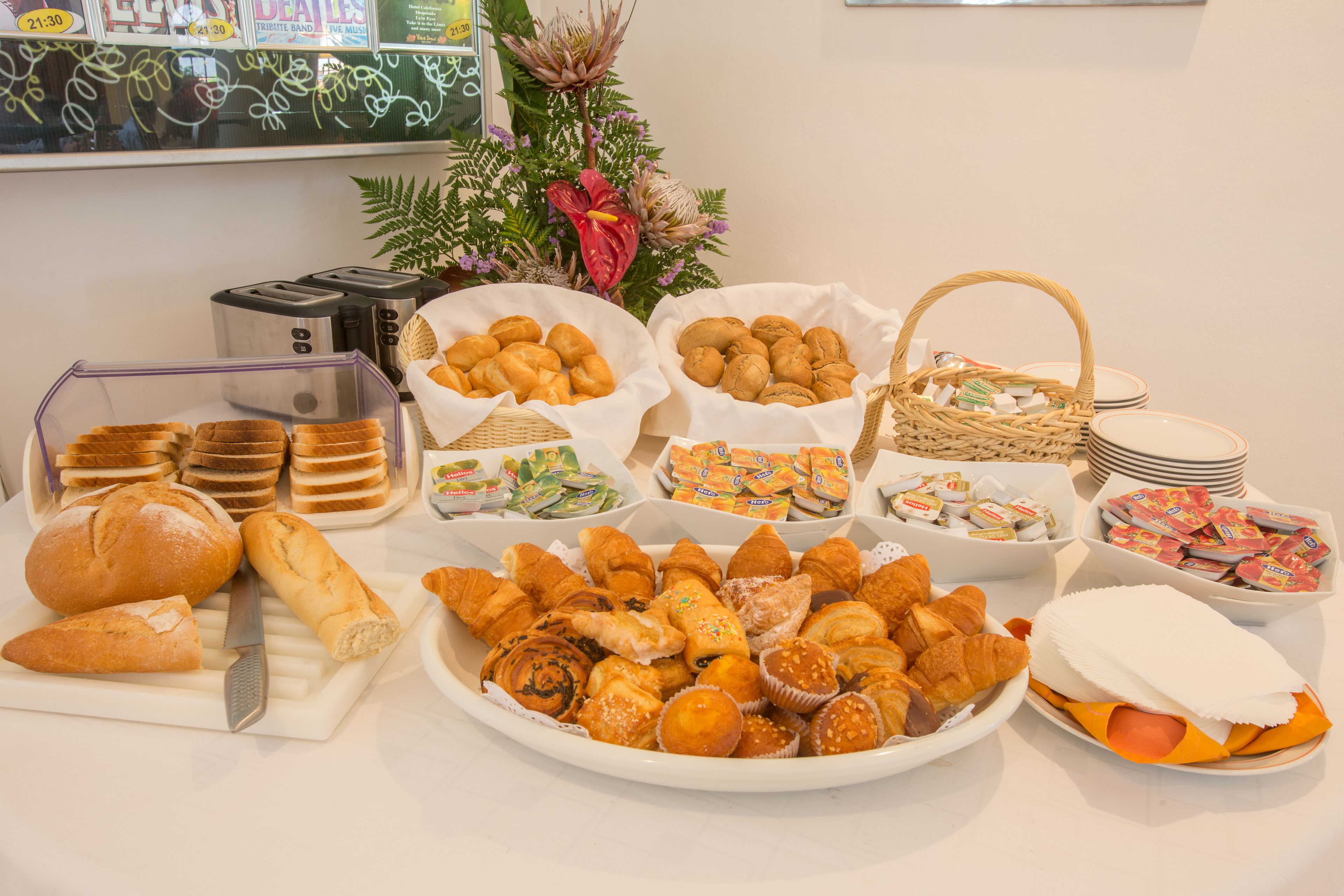 A buffet table with various pastries, bread, and condiments.