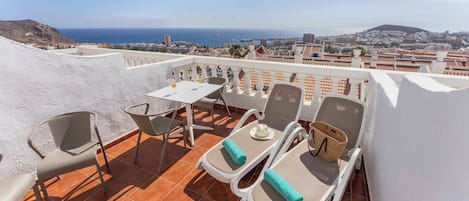 Una terraza con mesa y sillas, con vistas a un paisaje urbano costero.