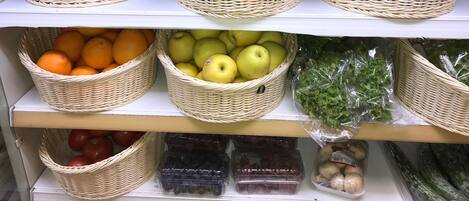 A grocery store shelf with baskets of fruits and vegetables.