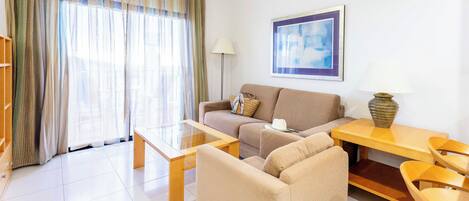A modern living room with a sofa, armchairs, a coffee table, and a lamp.