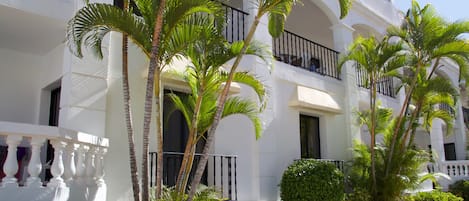 A white building with balconies and palm trees.