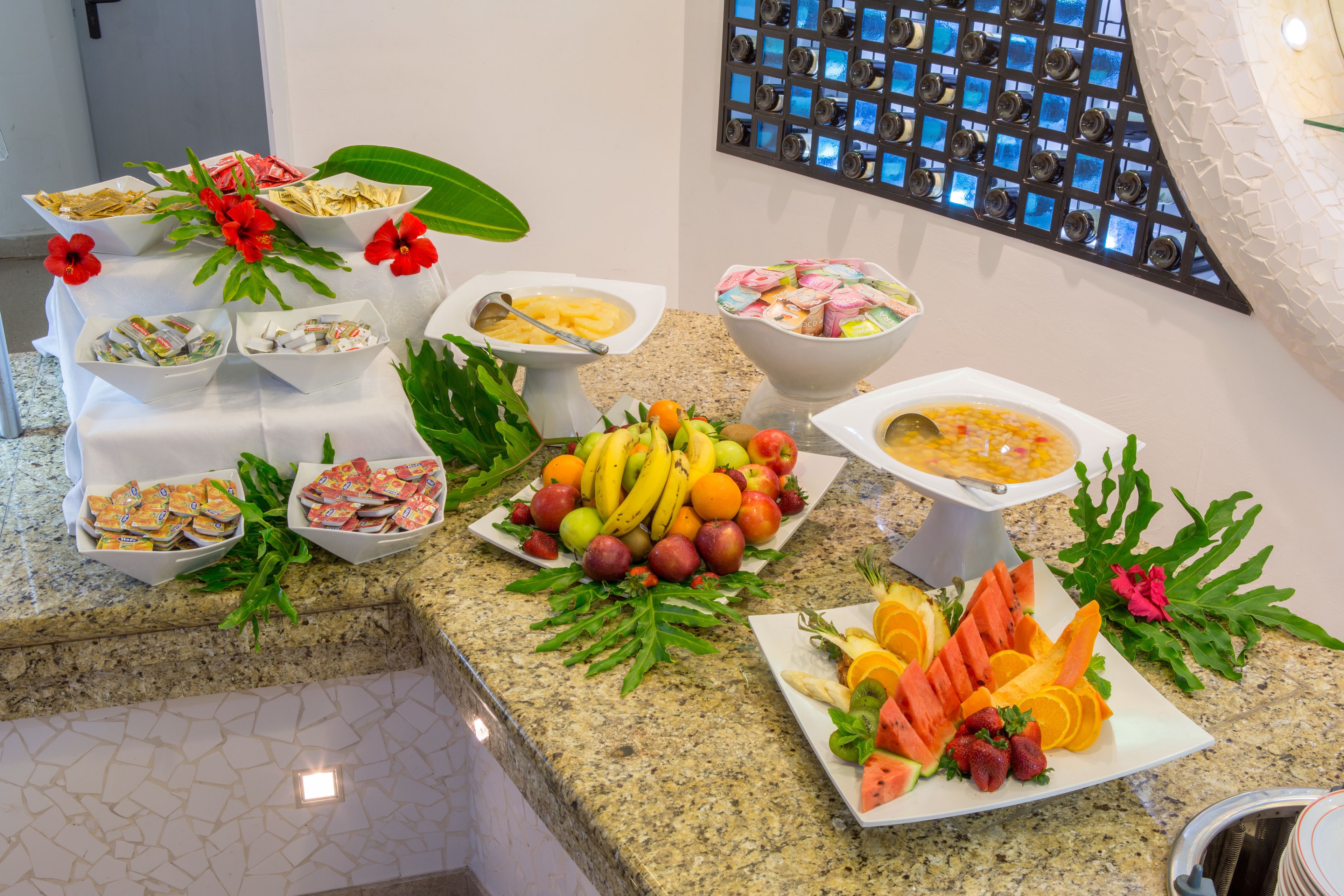 A buffet with various food items and a wine rack in the background.