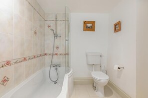 Une salle de bain avec une douche, des toilettes et un petit tableau encadré accroché au mur.