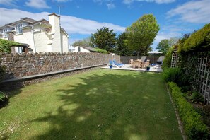 A stone wall, a grassy lawn, and a patio area with outdoor furniture. - 4 Bed in Braunton (oc-anchor) (Croyde)
