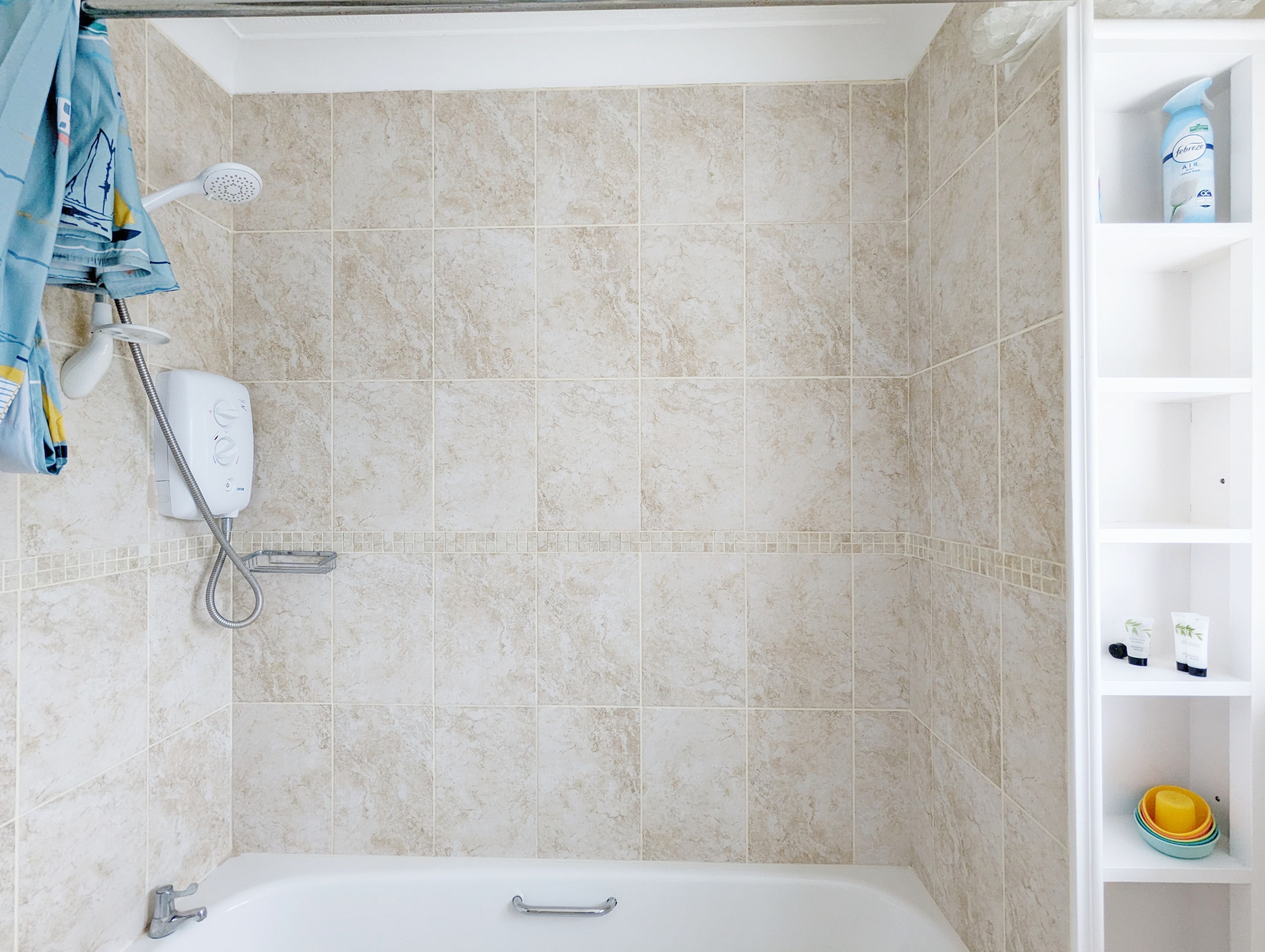 Un baño con bañera, ducha y un estante con artículos de aseo.