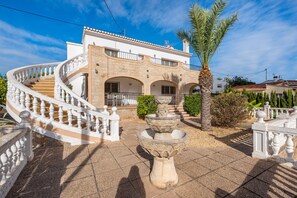 A two-story building with a curved staircase, a stone facade, and a central courtyard with a fountain.
