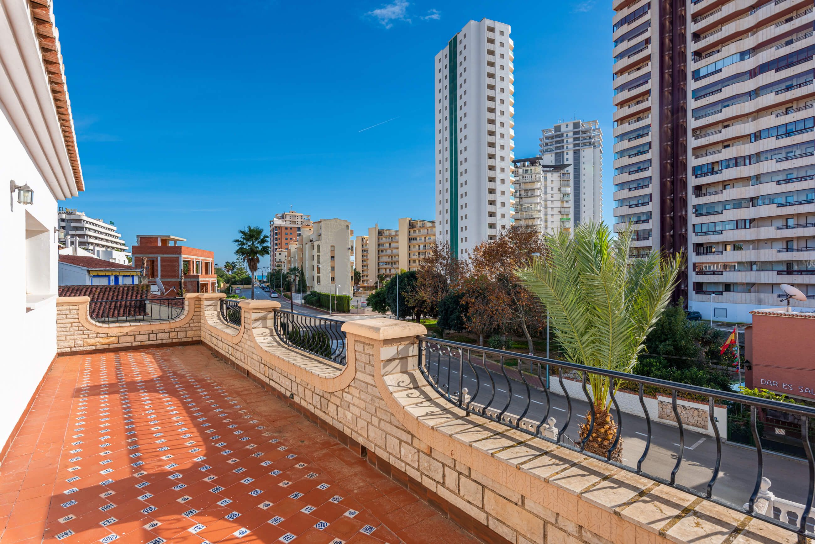 Una terrassa al terrat amb sòl de rajola, un mur de pedra corbat i una barana de metall.