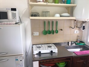 A kitchen with a white refrigerator, a microwave, a gas stove, and a sink.