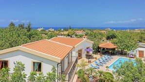 Ein Resort mit Swimmingpool, Liegestühlen und Meerblick.
