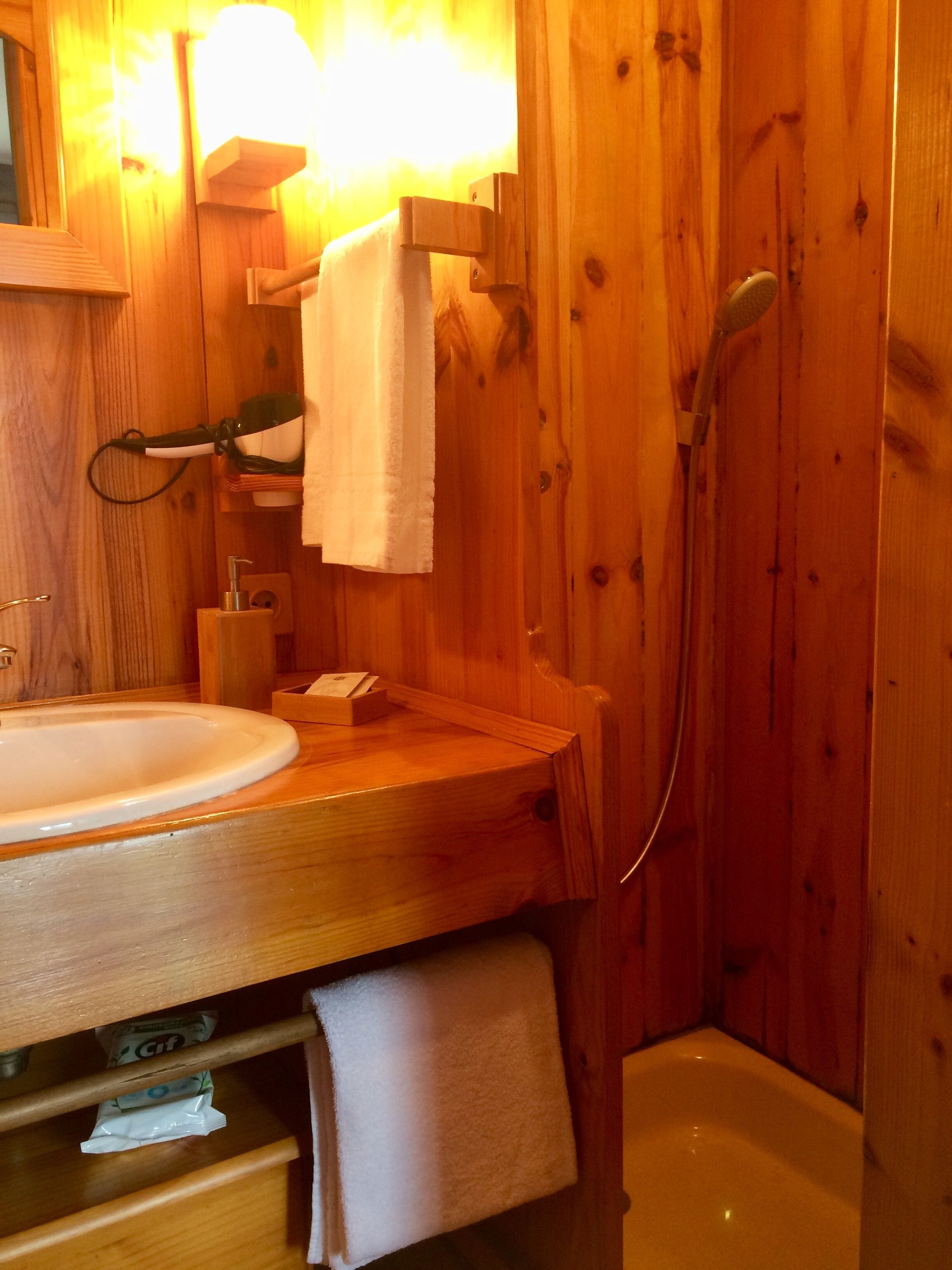 Ein Badezimmer aus Holz mit Waschbecken, Handtuchhalter und Dusche.